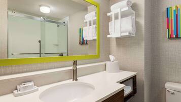A bathroom with a large mirror, a sink, a toilet, and a towel rack.