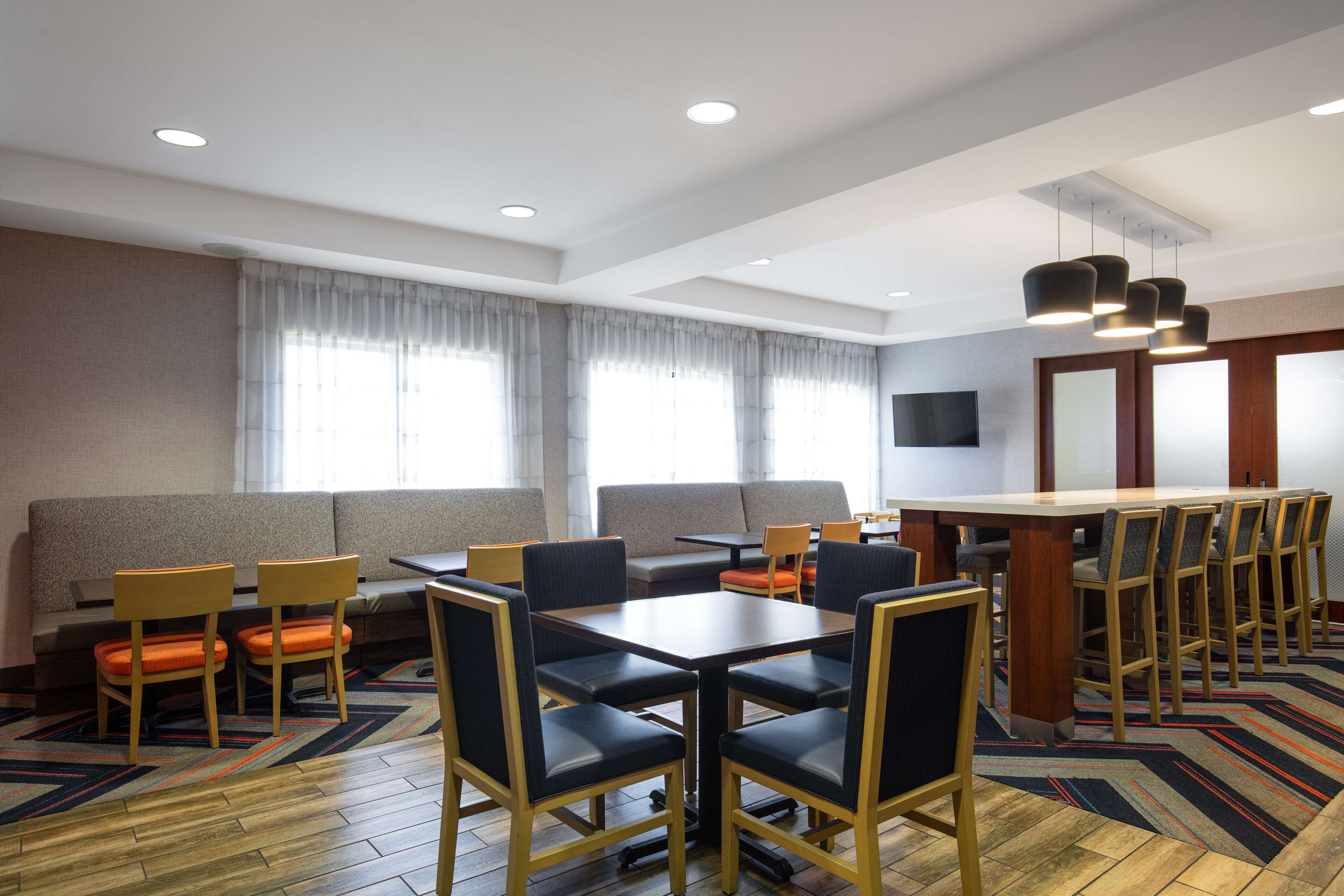 A modern hotel room with a dining area, a sofa, and a TV.