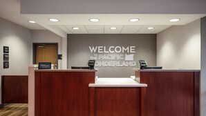 A reception desk with a "Welcome to the Pacific Wonderland" sign, a digital check-in station, and a "Hilton Honors" sign. - Hampton Inn Medford (Medford)