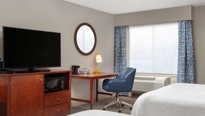A hotel room with a flat-screen TV, a desk with a lamp, a chair, and two beds. - Hampton Inn Medford (Medford)
