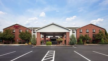 A Hampton Inn hotel with a brick facade, a covered entrance, and a parking lot.