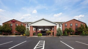A Hampton Inn hotel with a brick facade, a covered entrance, and a parking lot.