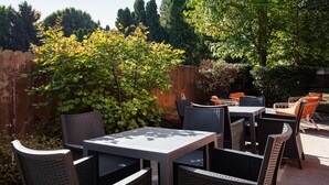 An outdoor patio area with wicker furniture and a wooden fence. - Hampton Inn Medford (Medford)