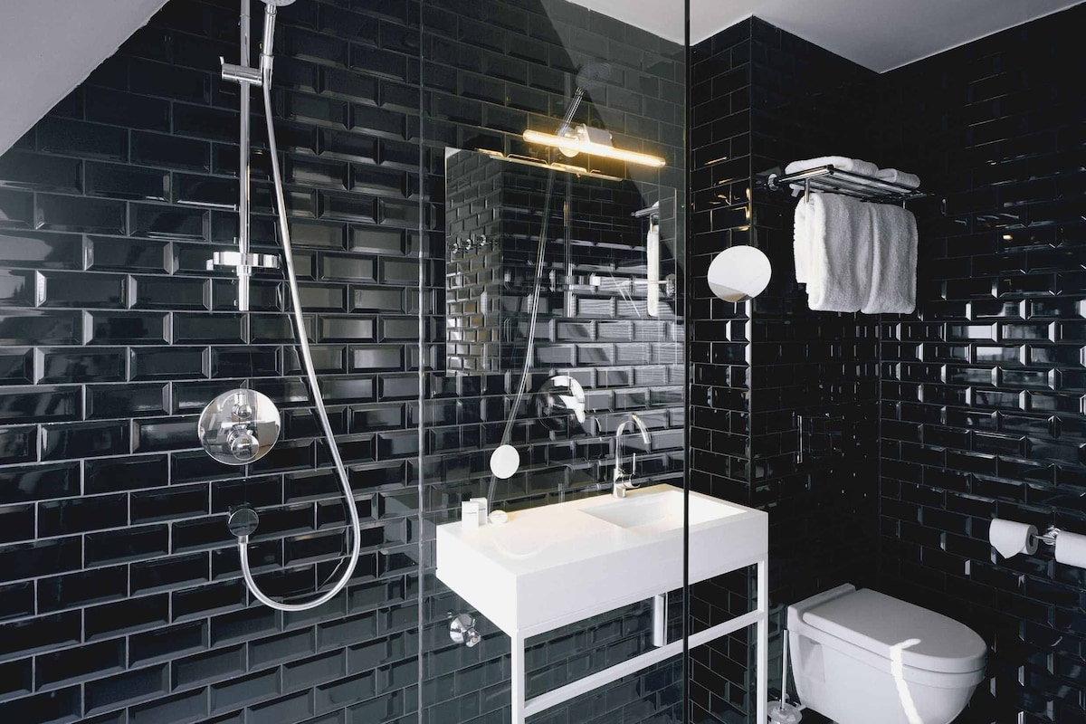 A modern bathroom with a glass-enclosed shower, a white sink, and a toilet.