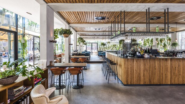 Un café moderno con techo de madera, barra y mesas.