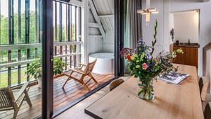 Una terraza de madera con una mesa de comedor, sillas y un jarrón de flores.