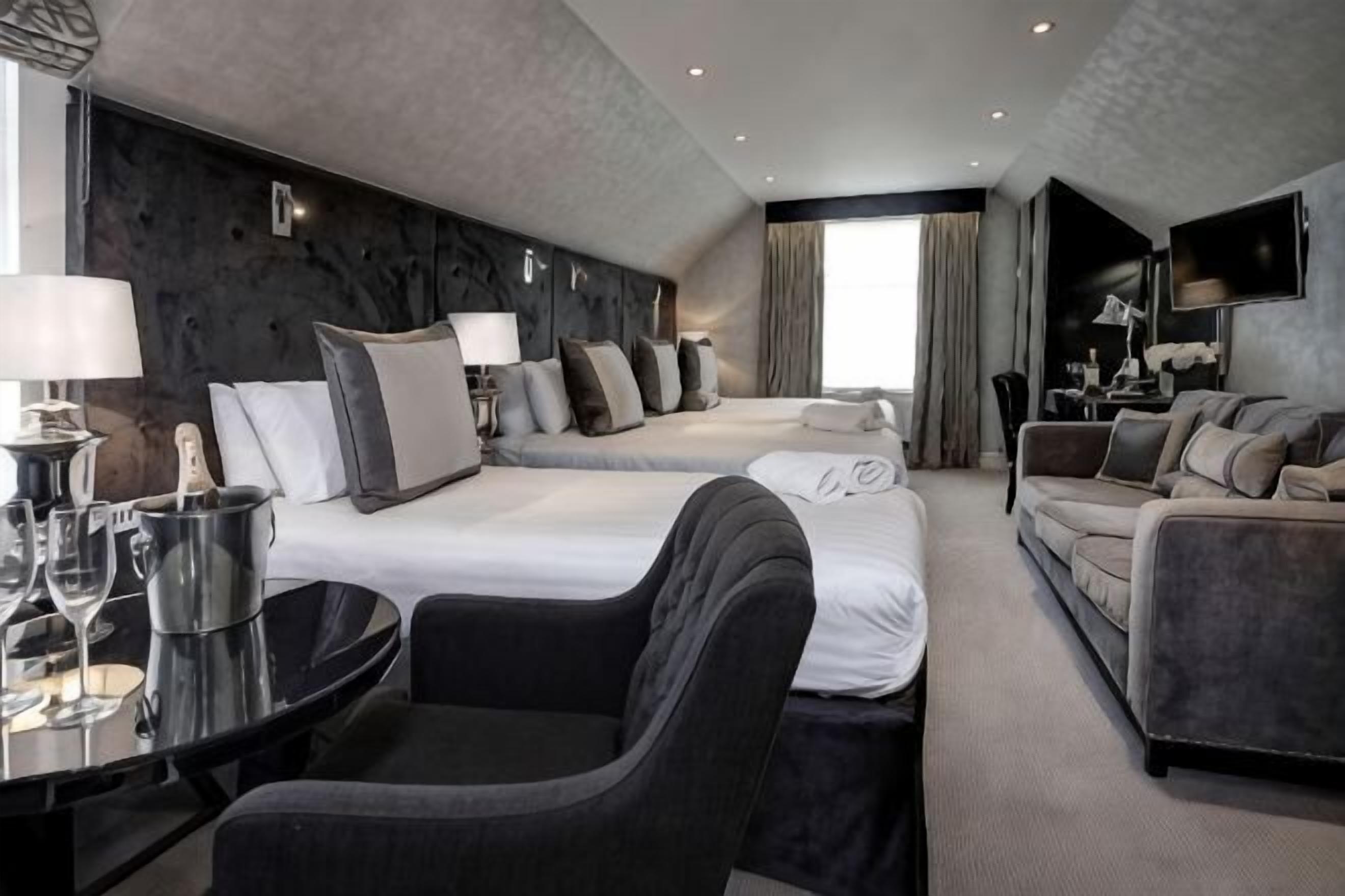 Ett hotellrum med två sängar, en soffa, ett matbord och en TV.