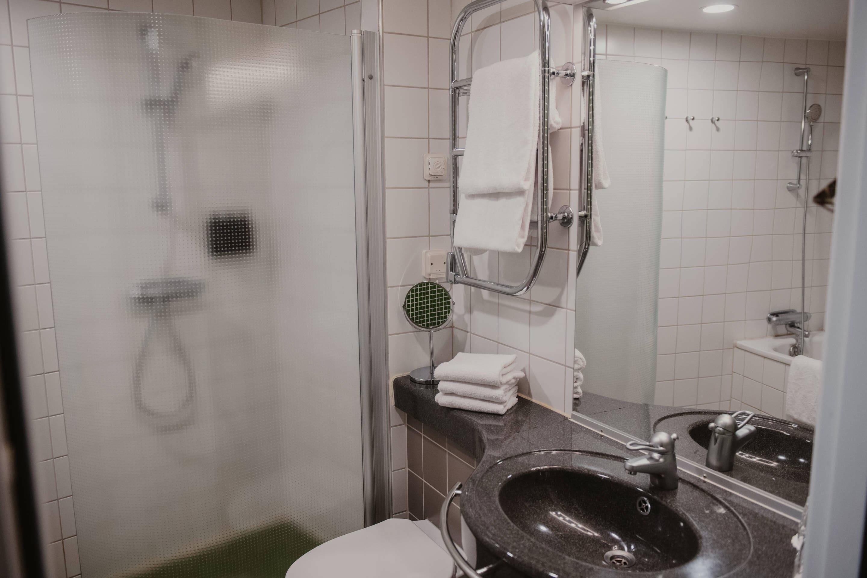 Une salle de bain moderne équipée d’une douche, de toilettes, d’un lavabo et d’un porte-serviettes.