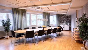 Een vergaderruimte met een lange tafel, zwarte stoelen en een kroonluchter.