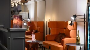 Een moderne woonkamer met oranje banken, een ronde tafel en een klein tafeltje met een fles.