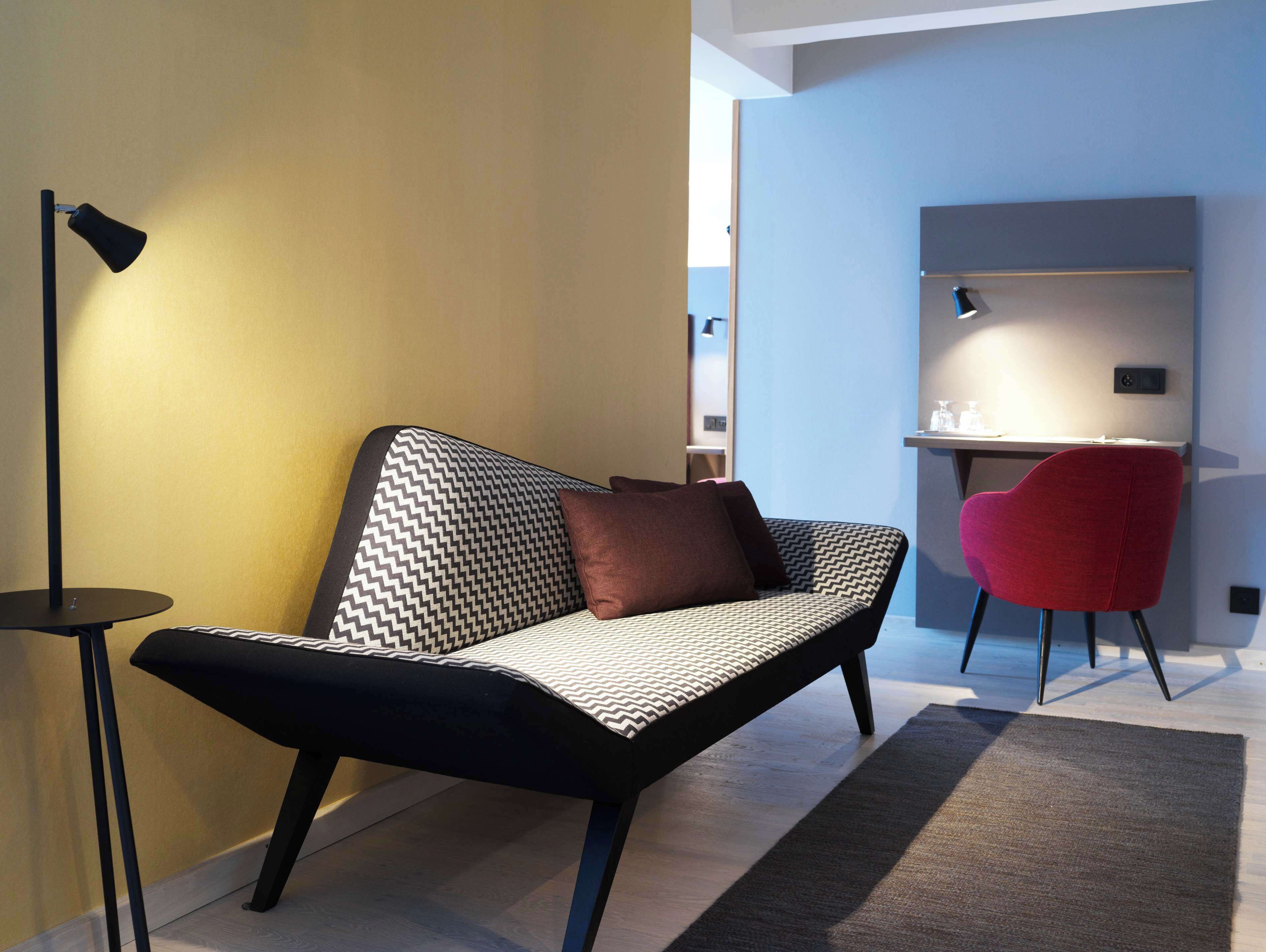 Un espacio moderno para vivir con un sofá, una silla roja y un escritorio.