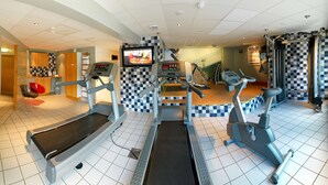 Een fitnessruimte met loopbanden, elliptische trainers en een televisiescherm.