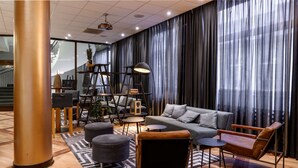 Een moderne woonkamer met een bank, poefjes, een salontafel en een boekenkast.