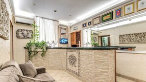 Un espace d’accueil avec un canapé, un téléviseur et un mur décoratif.