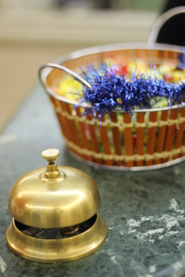 A brass bell and a wicker basket with tinsel on a countertop. - Hotel Orlanda (Rome)