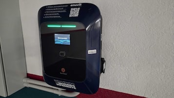 A StarCharge electric vehicle charging station with a welcome screen, located near a hotel entrance.