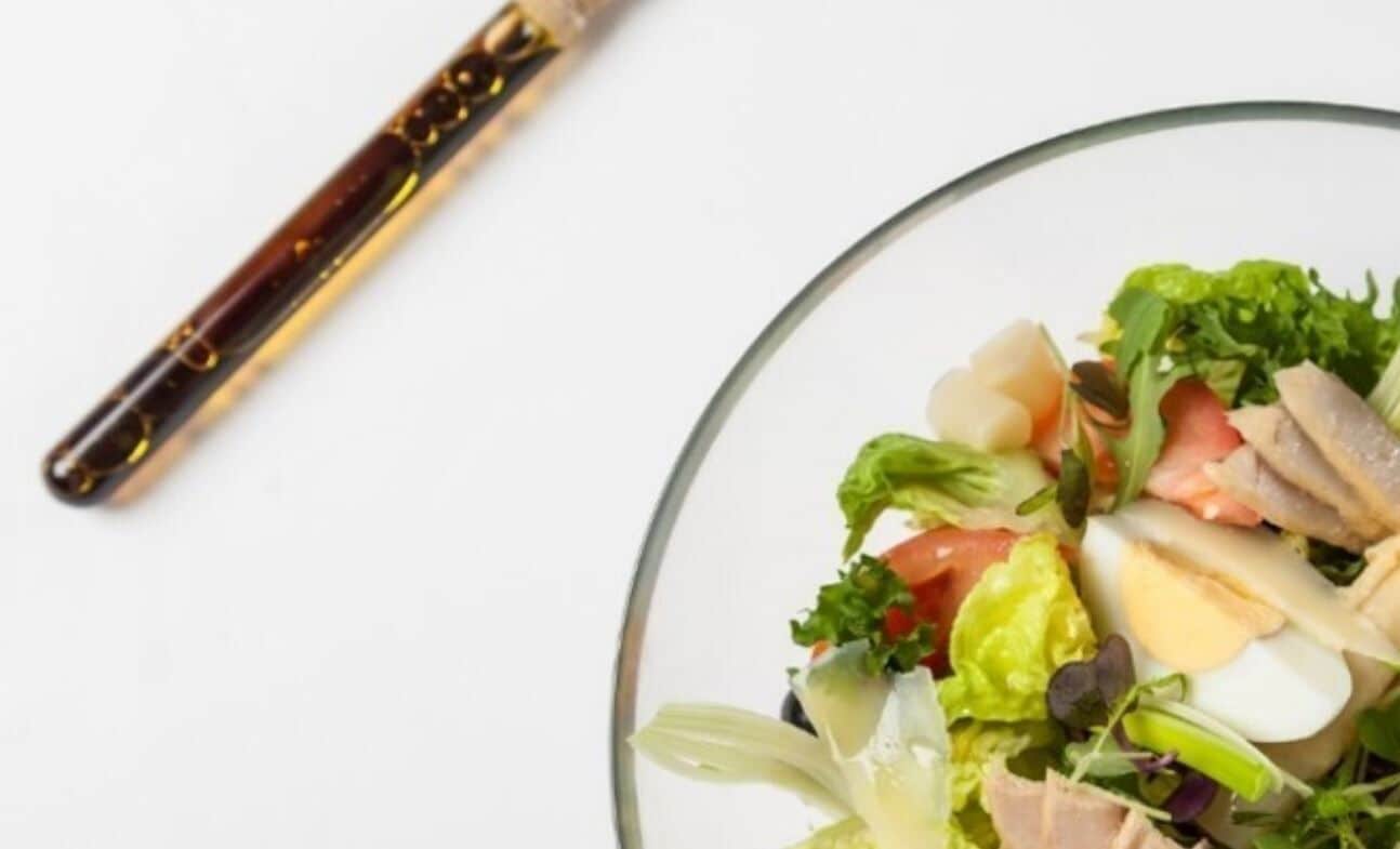 A clear view of a salad bowl with various ingredients, a knife, and a glass plate.