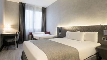 A hotel room with a large bed, a desk, and a chair.