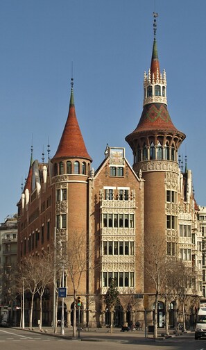 Un edificio histórico con dos torres destacadas, una con techo cónico y la otra con aguja.