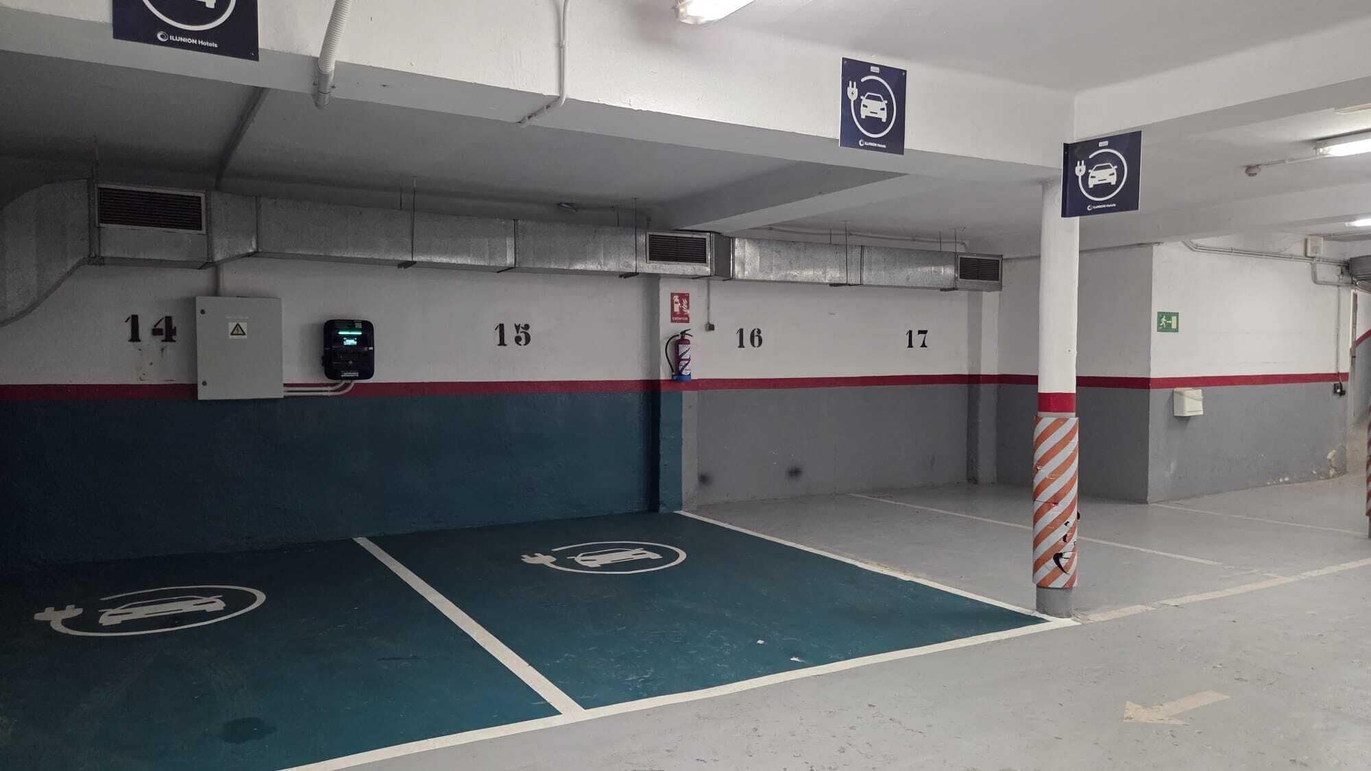 Eine Parkgarage mit nummerierten Parkplätzen, einem Feuerlöscher und einem Feuer Schlauch an der Wand.