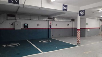 Eine Parkgarage mit nummerierten Parkplätzen, einem Feuerlöscher und einem Feuer Schlauch an der Wand.