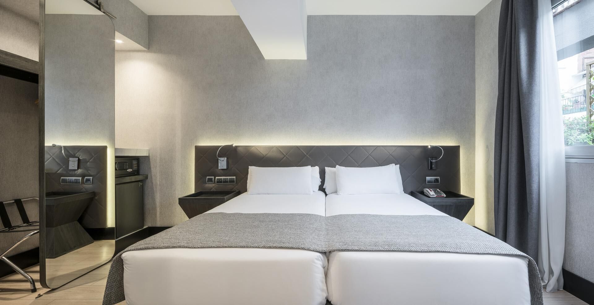 Moderni hotellihuone, jossa on suuri sänky, yöpöydät, työpöytä ja tuoli.
