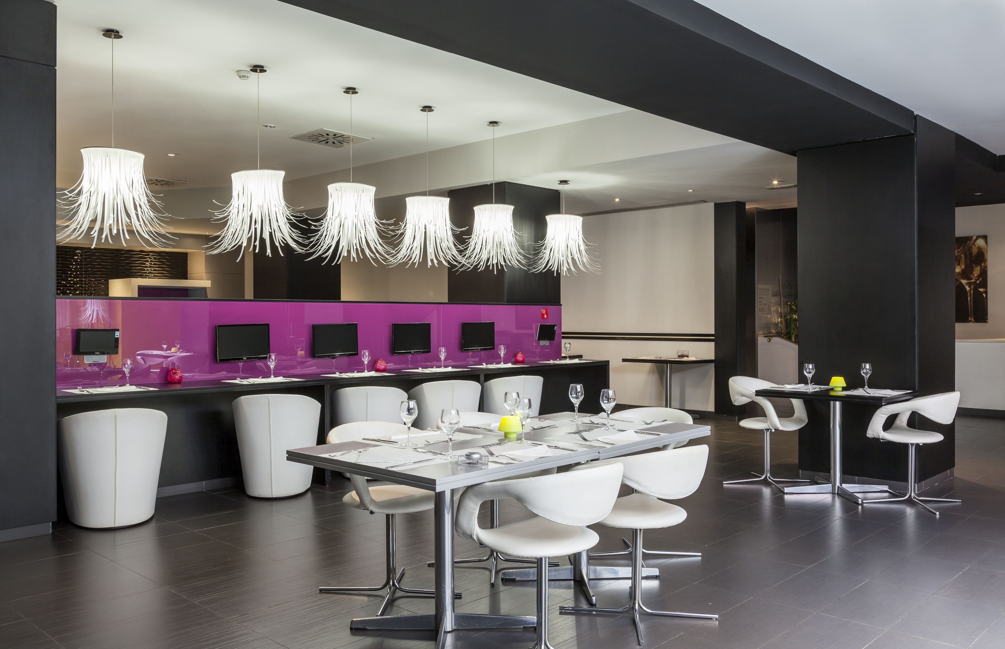 A modern dining area with a long table, white chairs, and pendant lights.