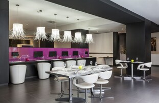 A modern dining area with a long table, white chairs, and pendant lights.