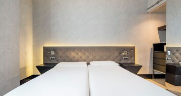 A double bed with a tufted headboard, two bedside tables, and a nightstand with a lamp.