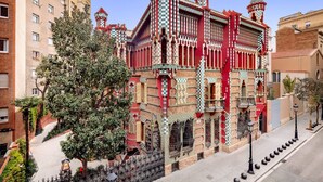 Un edificio con patrones ornamentales de cuadros rojos y verdes, ventanas amplias y una torre destacada.