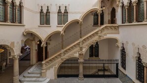 Una gran escalera con barandillas ornamentadas y múltiples arcos, que conduce a diferentes niveles de un edificio con detalles decorativos y columnas.