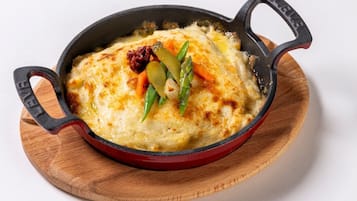 Une poêle en fonte contenant un plat cuit au four, probablement un gratin, posée sur une planche en bois.