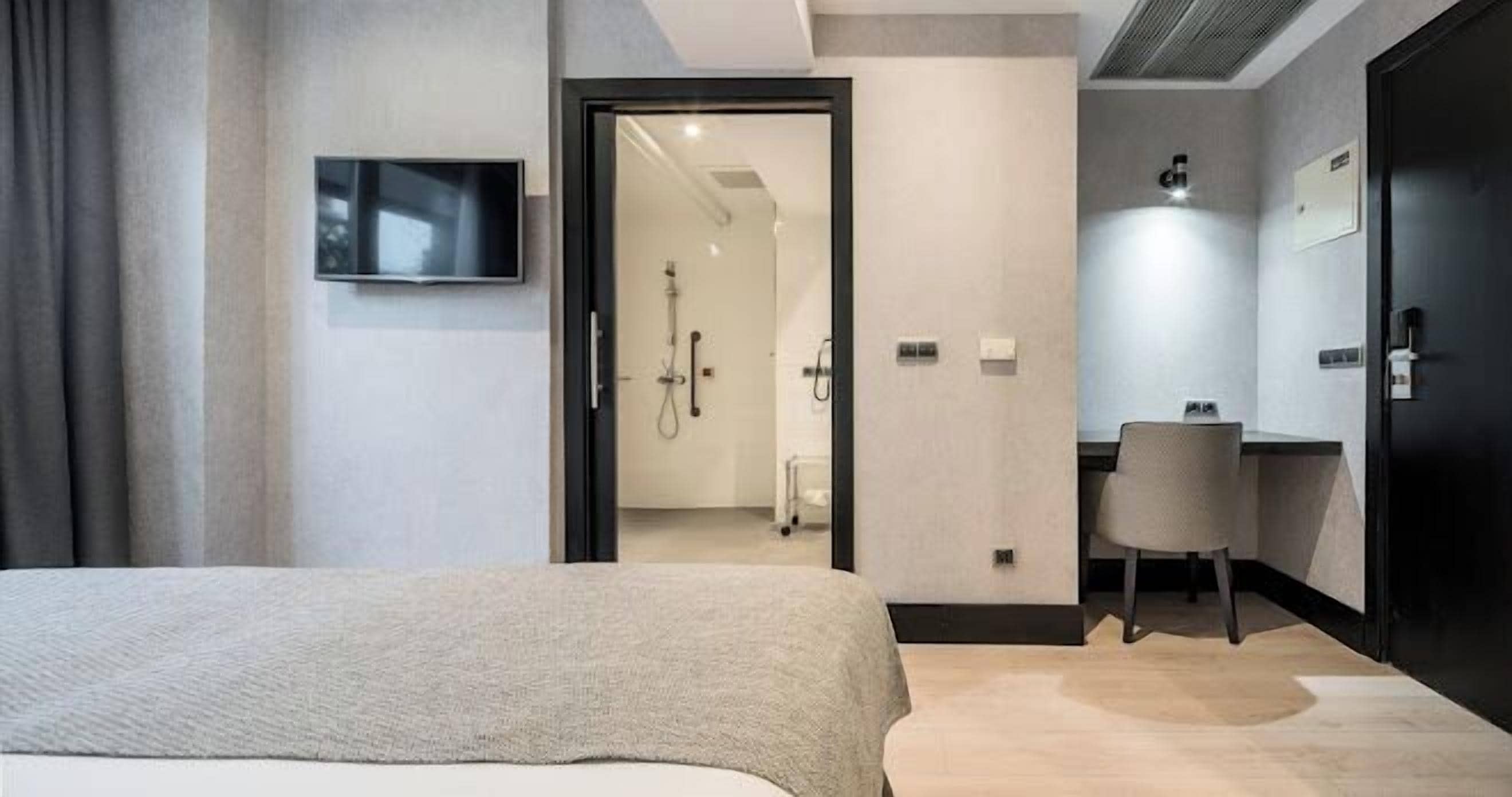 Een moderne hotelkamer met een bed, bureau en douche.