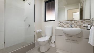 Un baño moderno con cabina de ducha de vidrio, inodoro y lavabo con salpicadero de azulejos.