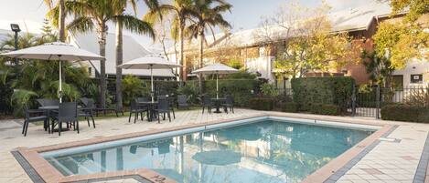 Una piscina al aire libre, sombrillas, sillones reclinables de piscina