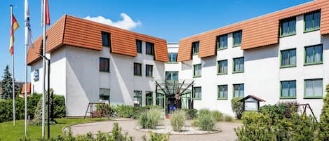 A two-story building with a symmetrical facade, multiple windows, and a central entrance with a glass canopy.