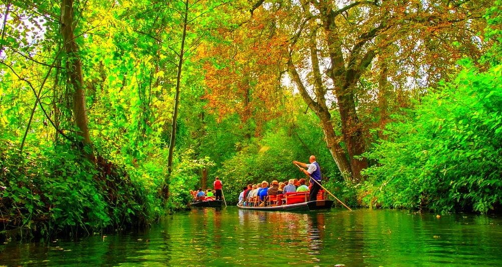 A river scene with boats, passengers, and a guide.