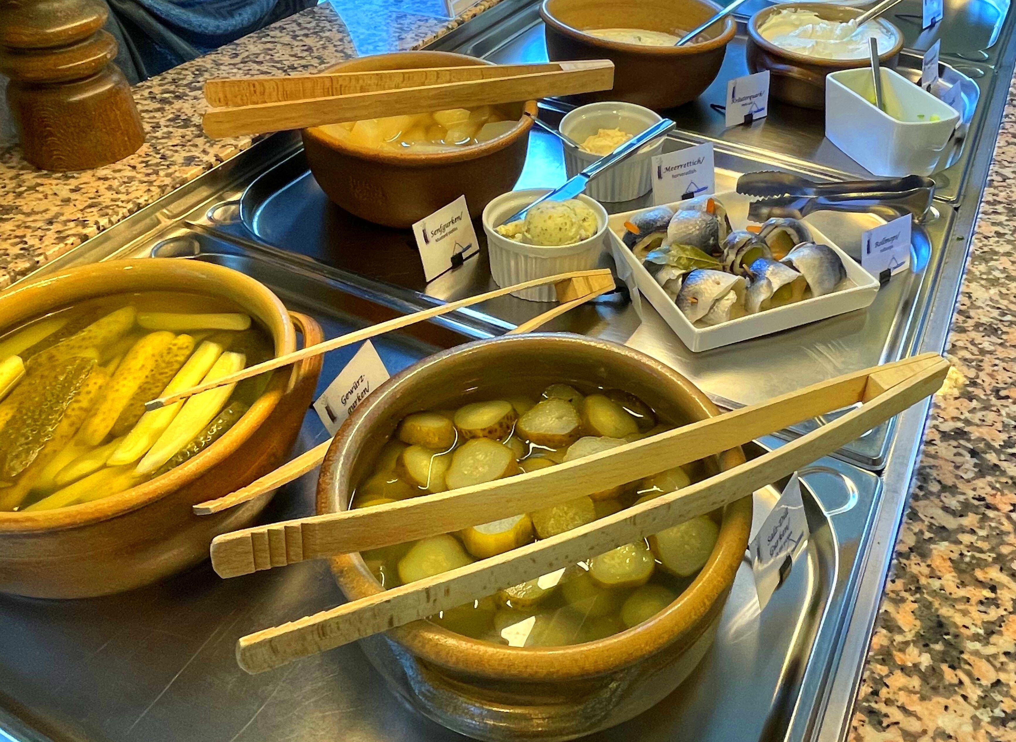 Un buffet proposant divers plats, notamment des légumes marinés, du poisson et des sauces.
