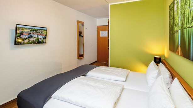 A hotel room with a bed, a painting on the wall, a mirror, and a door. - Best Western Spreewald (Lübbenau/Spreewald)