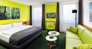 A hotel room with a bed, a sofa, a small table, and two chairs. - Best Western Spreewald (Lübbenau/Spreewald)