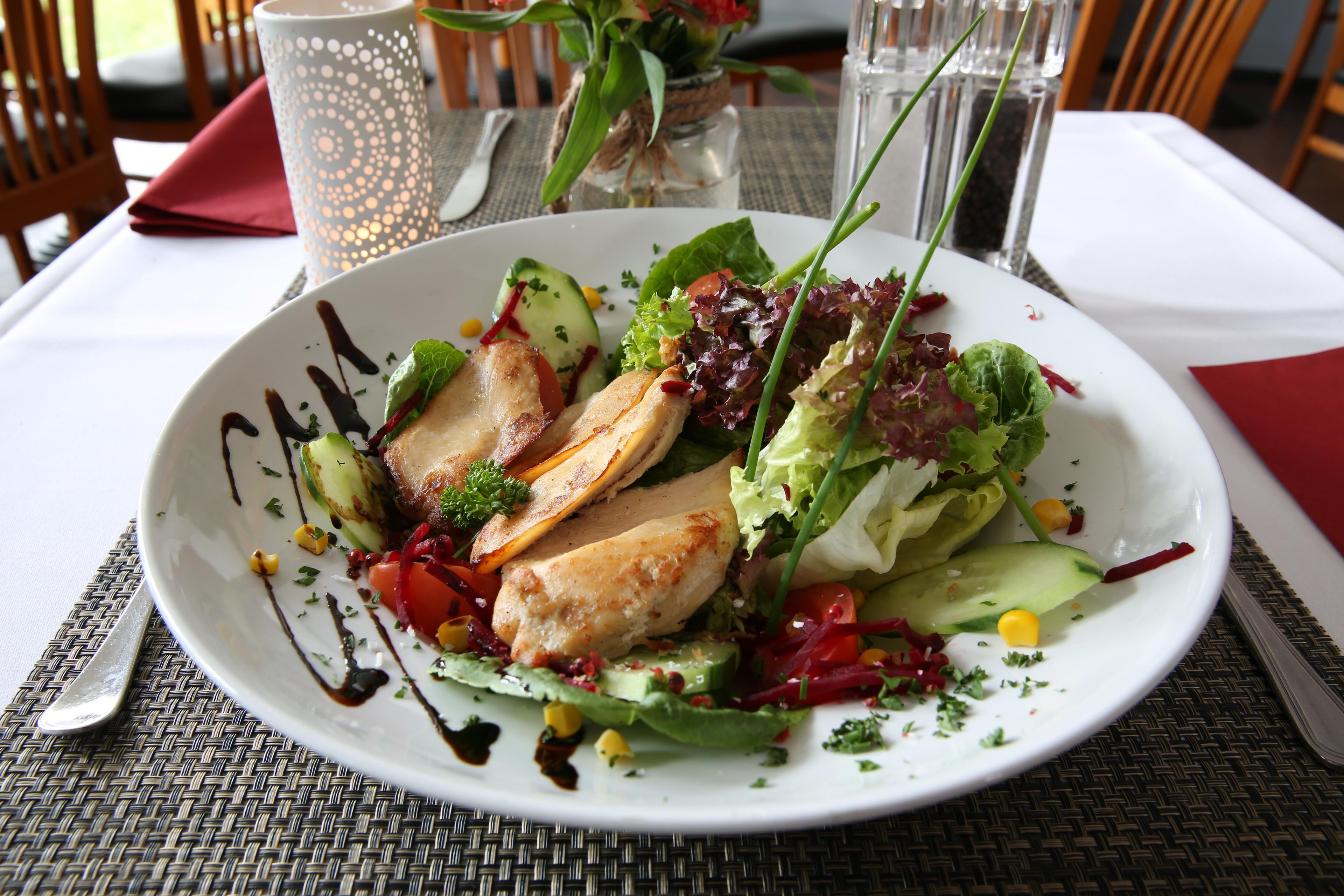 Une assiette contenant divers légumes et un morceau de viande, peut-être du poulet, le tout présenté sur une assiette blanche.