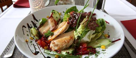 Une assiette contenant divers légumes et un morceau de viande, peut-être du poulet, le tout présenté sur une assiette blanche.