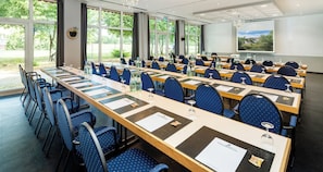 A conference room with multiple tables and chairs, large windows, and a projector screen. - Best Western Spreewald (Lübbenau/Spreewald)
