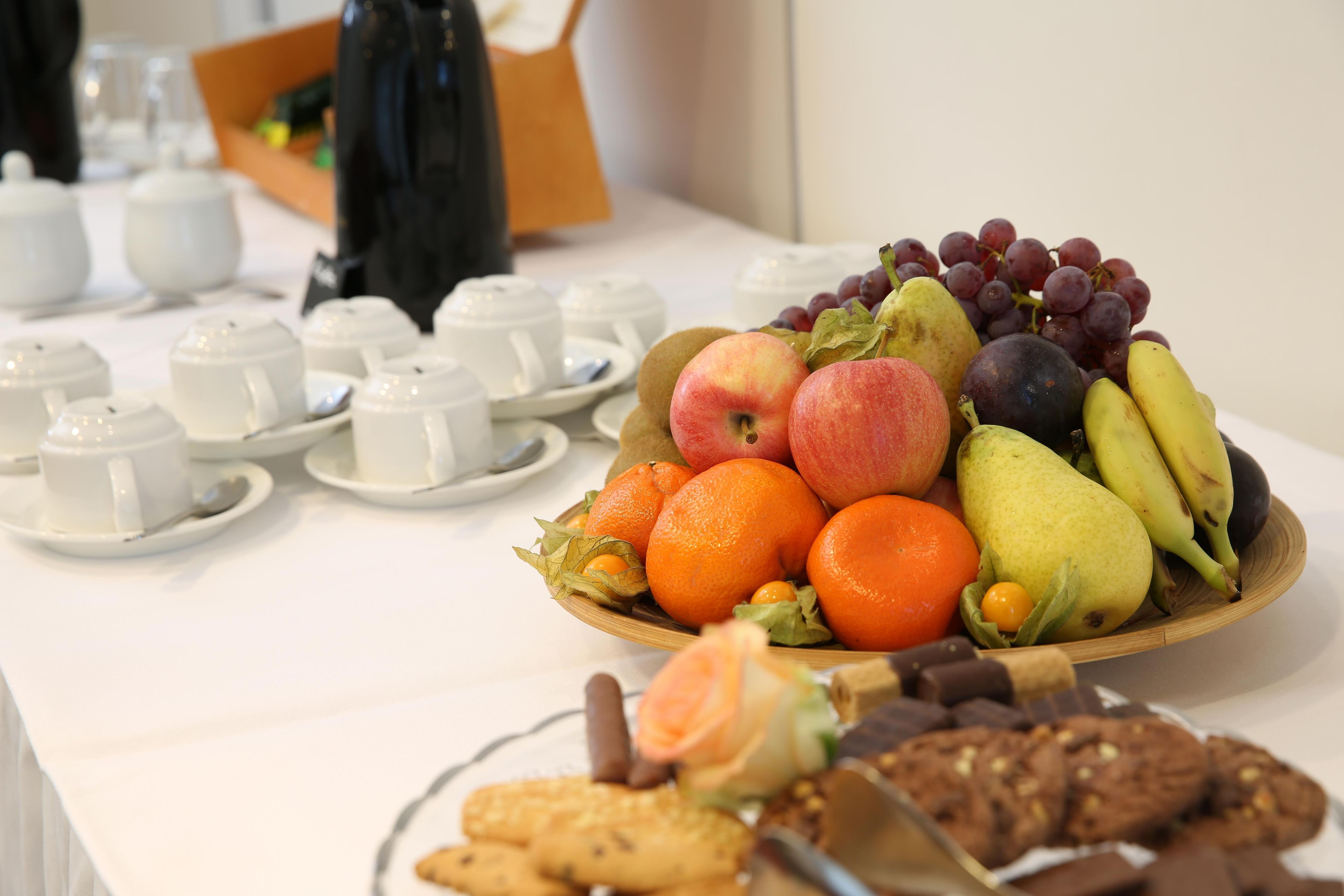 A table with a fruit bowl, teapots, and teacups.