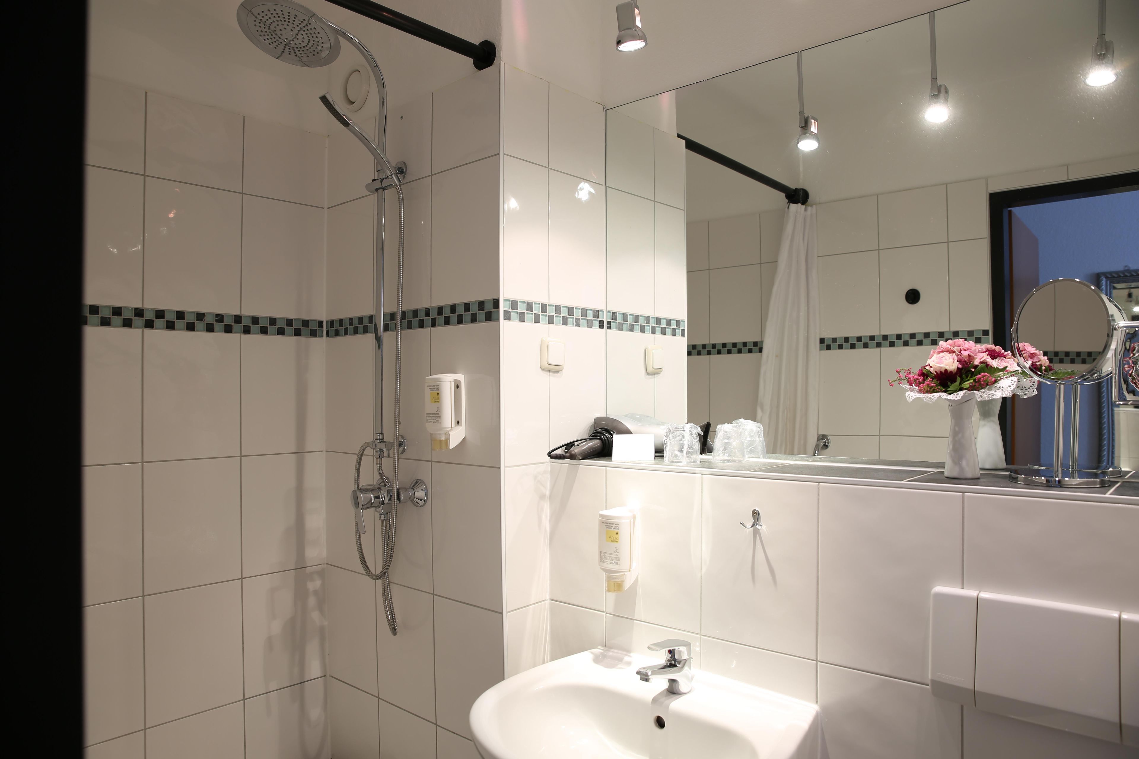 Une salle de bain moderne avec une douche, un lavabo et un miroir.