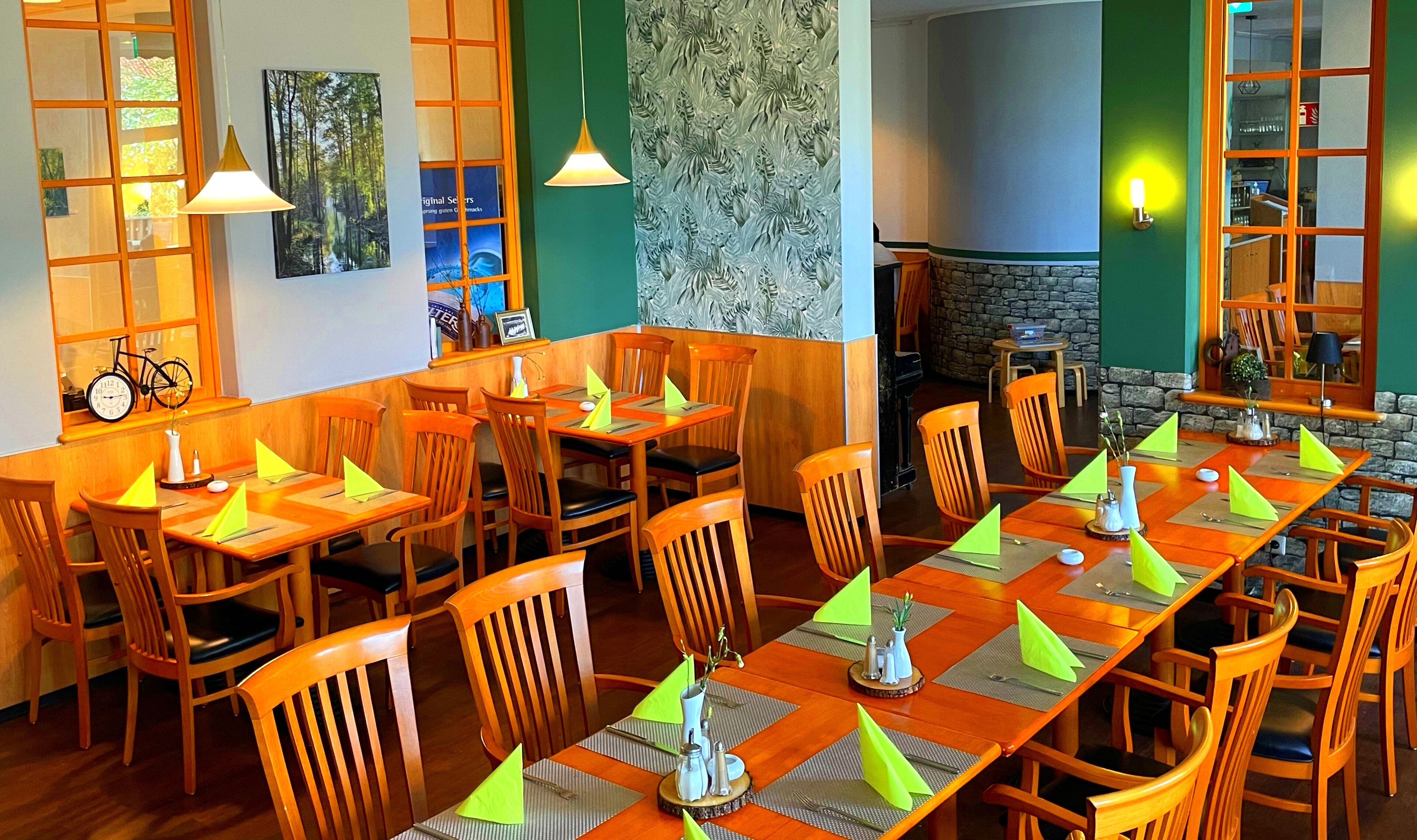 Un restaurant amb taules i cadires de fusta, parets verdes i una llar de pedra.