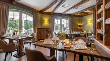 En restaurant med træbjælker, store vinduer og borde dækket til spisning.