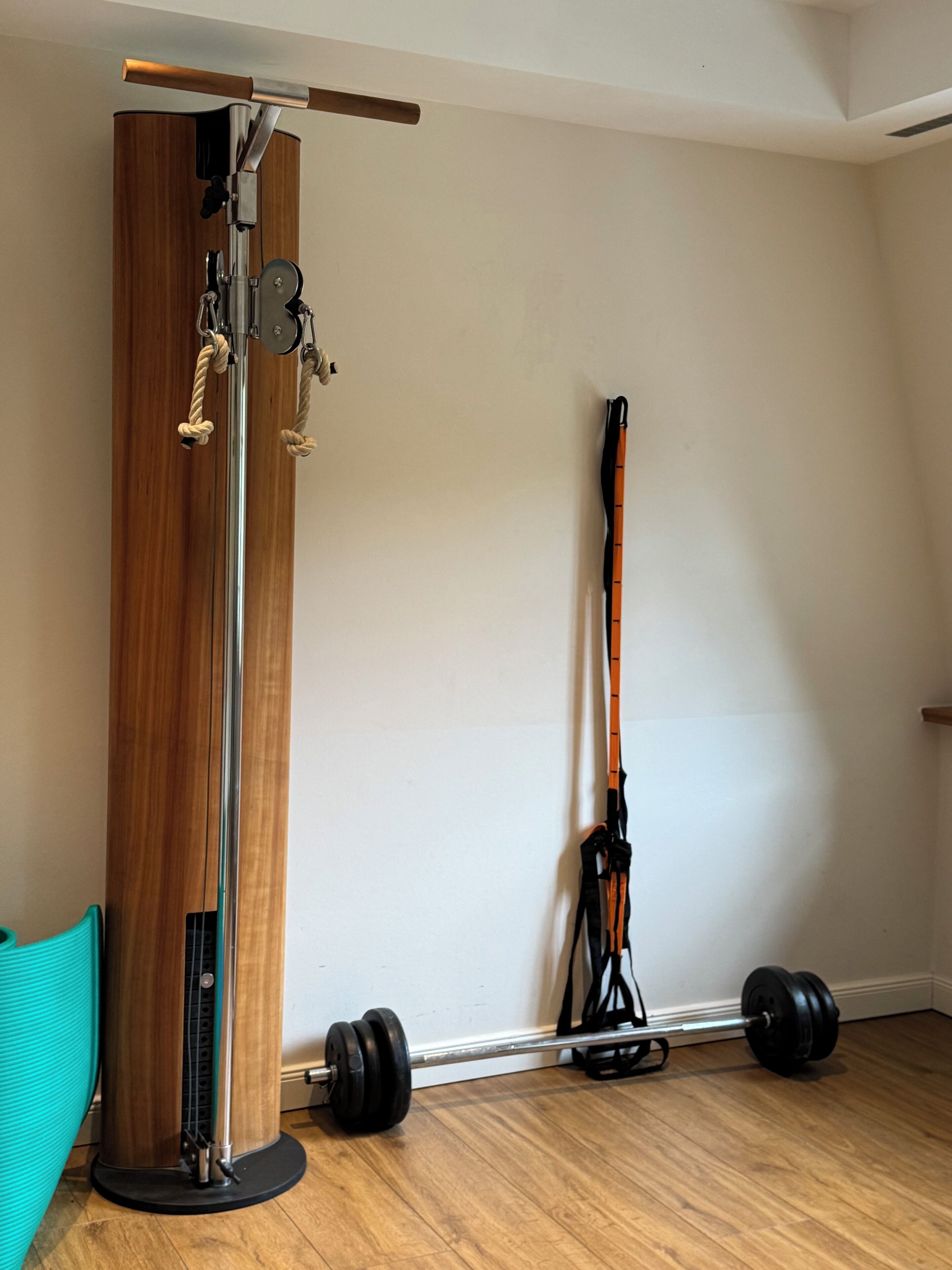 A gym with a pull-up bar, a standing exercise machine, a resistance band, and a yoga mat.
