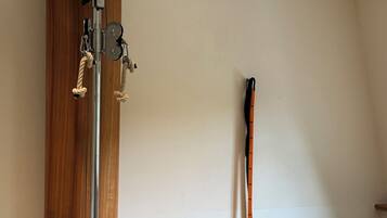 A gym with a pull-up bar, a standing exercise machine, a resistance band, and a yoga mat.