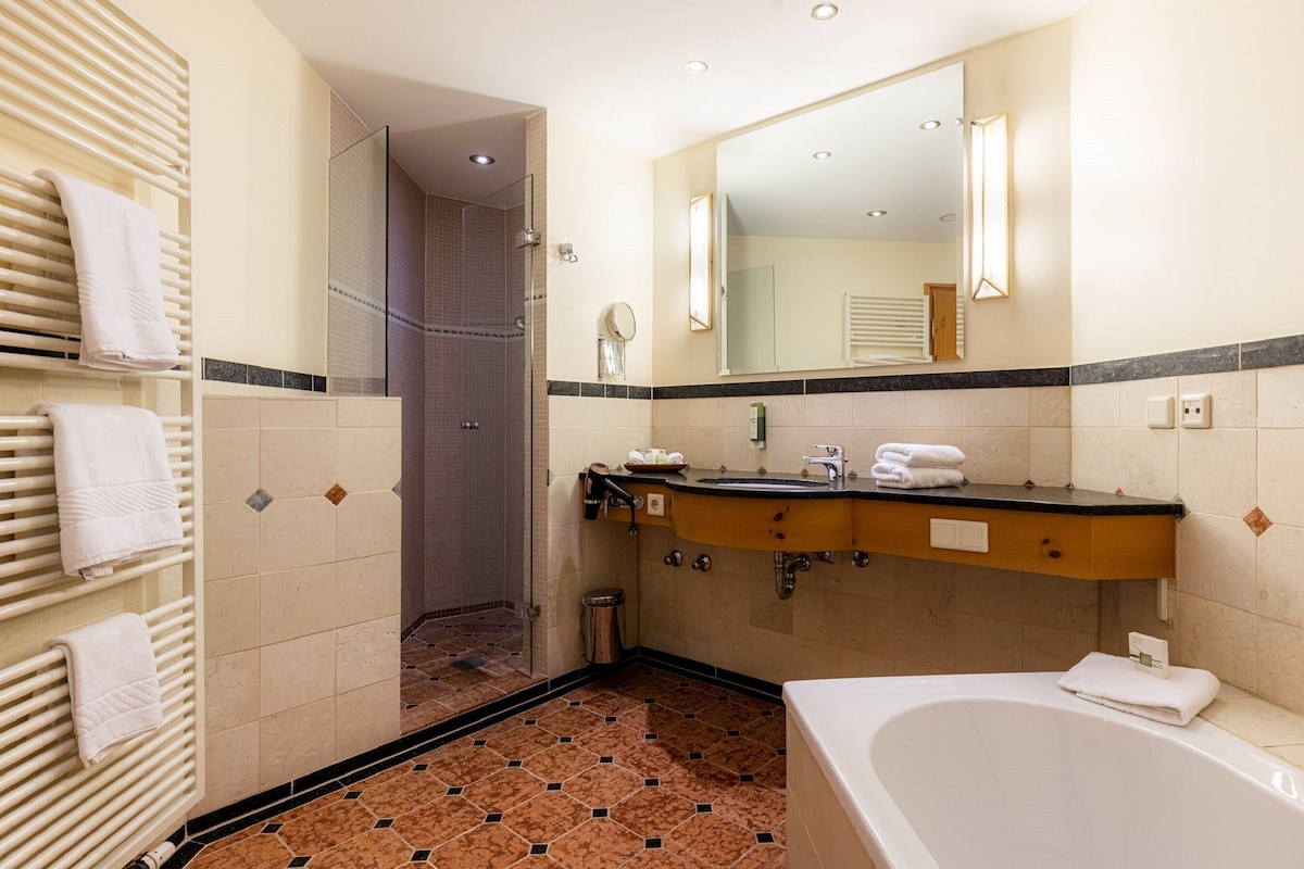 Un baño con bañera, ducha, tocador con lavabo y espejo.